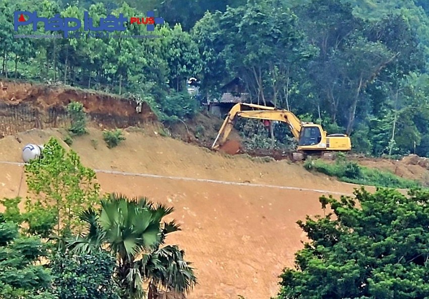 Máy xúc cỡ lớn đứng hiên ngang trên đỉnh ta luy con đường mới mở để múc đất đi bán.