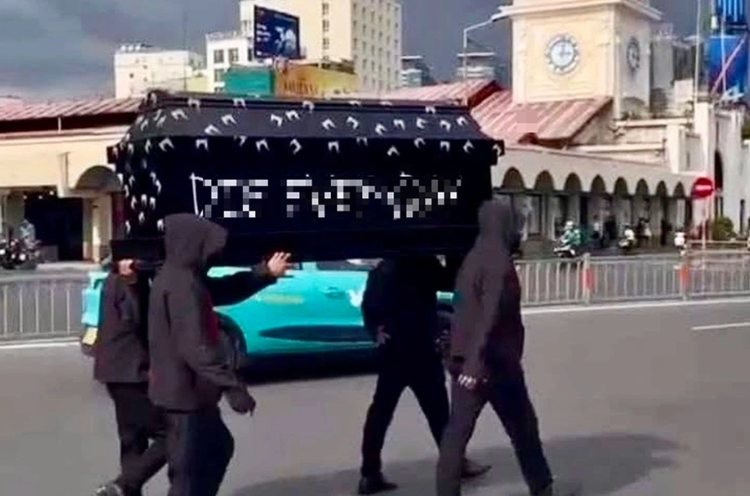 Nhóm 4 người mặc đồ đen, trùm đầu, khiêng quan tài trước chợ Bến Thành 