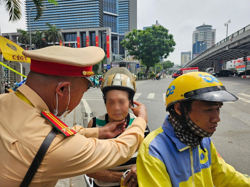Trung tá Kiều Văn Trung, cán bộ Đội CSGT đường bộ số 3, Phòng CSGT CATP Hà Nội hỗ trợ cụ bà lớn tuổi gặp khó khăn khi di chuyển giữa trưa nắng.