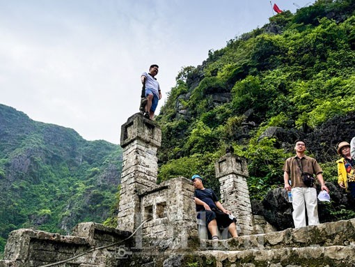 Bất chấp cảnh báo nguy hiểm, du khách vô ý thức vẫn leo lên đầu cột cheo leo tại Hang Múa khiến nhiều người bất bình. (Ảnh: Lê Hoàng)