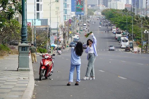 Hai bạn trẻ xuống lòng đường chụp hình theo trend, gây nguy cơ tai nạn giao thông. (Ảnh: Phú Ngân)