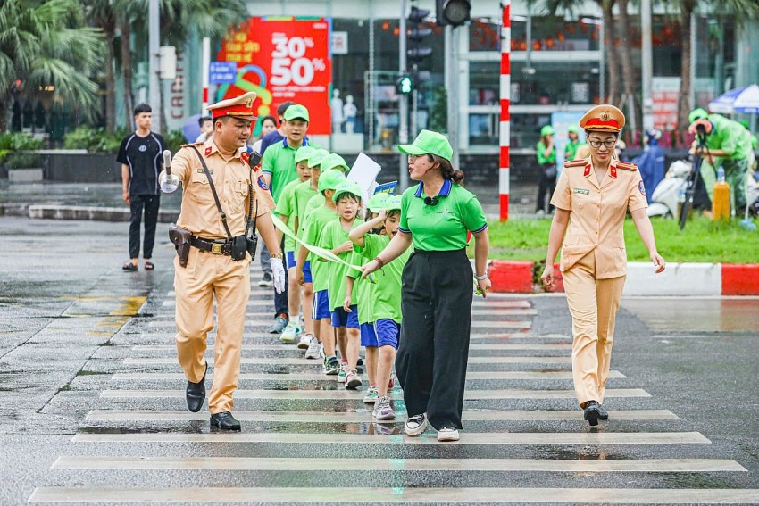 Cán bộ CSGT hướng dẫn học sinh cách sang đường đúng tín hiệu đèn và vạch kẻ đường.