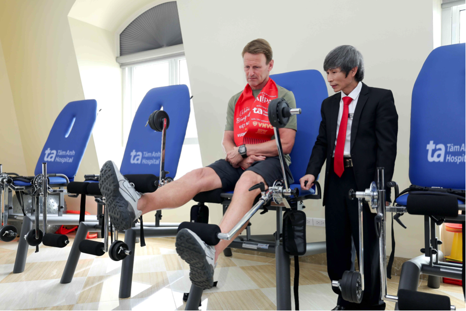 ThS Trần Văn Dần, KTV trưởng khoa Phục hồi chức năng, BVĐK Tâm Anh Hà Nội hướng dẫn danh thủ Teddy Sheringham tập luyện trên hệ thống thiết bị rèn luyện và tăng cường sức mạnh cho cơ tứ đầu đùi.