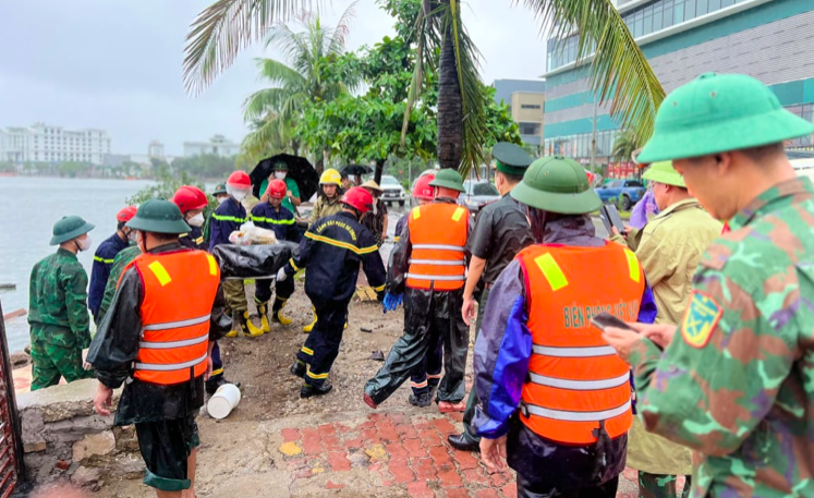 Các lực lượng cứu hộ đưa thi thể lên bờ. Ảnh QMG Các lực lượng cứu hộ đưa thi thể lên bờ. Ảnh QMG