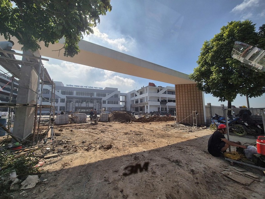 Công nhân xây dựng không có bảo hộ lao động vẫn đang chèo giáo để thực hiện việc chát tường hạng mục cổng chính của Trường THPT Phúc Thịnh.