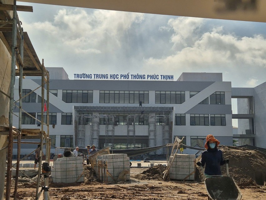 Công nhân đẩy xe rùa ra chở vật liệu vào để thực hiện việc lát nền sân trường.