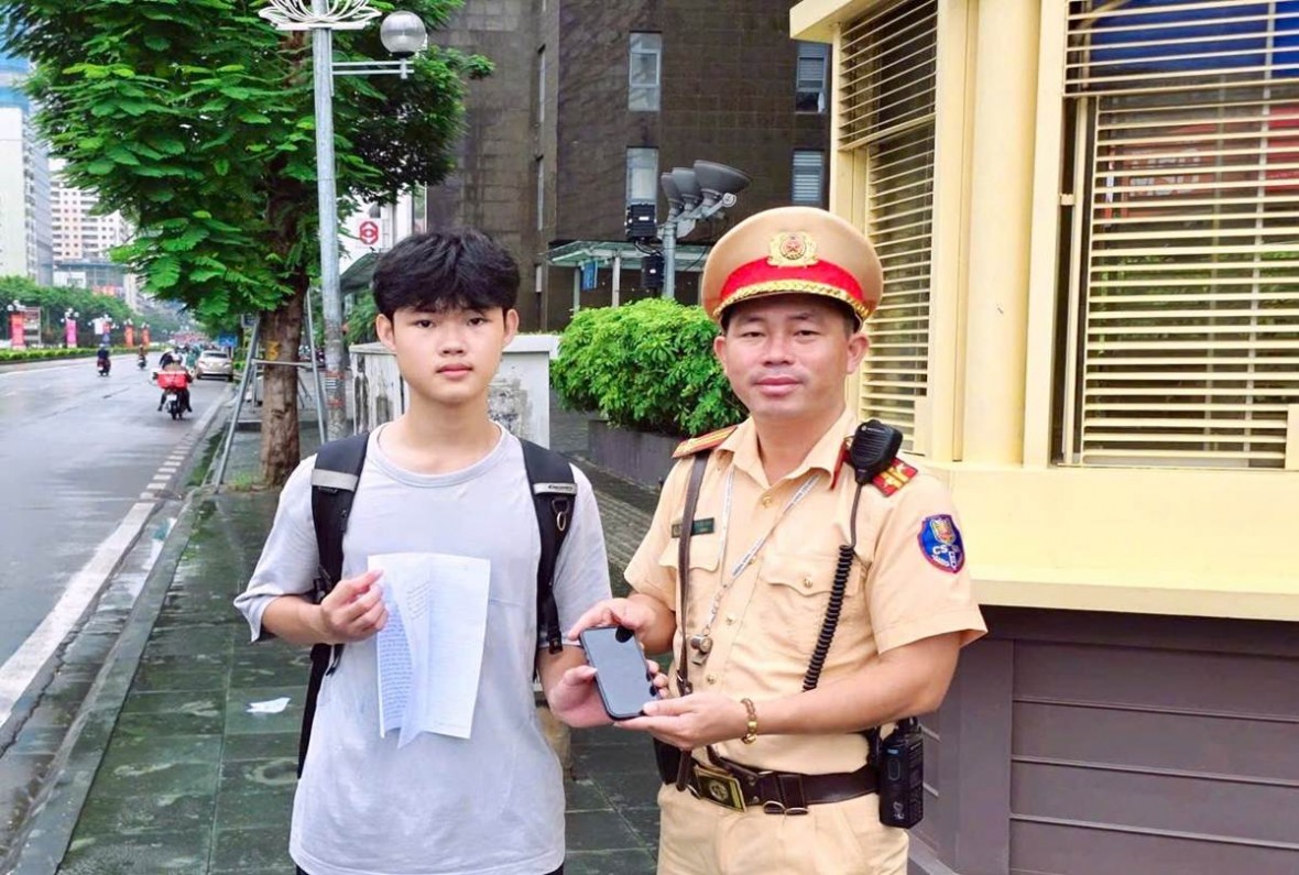 Trung tá Nguyễn Việt Anh trao lại chiếc điện thoại bị cho nam sinh.