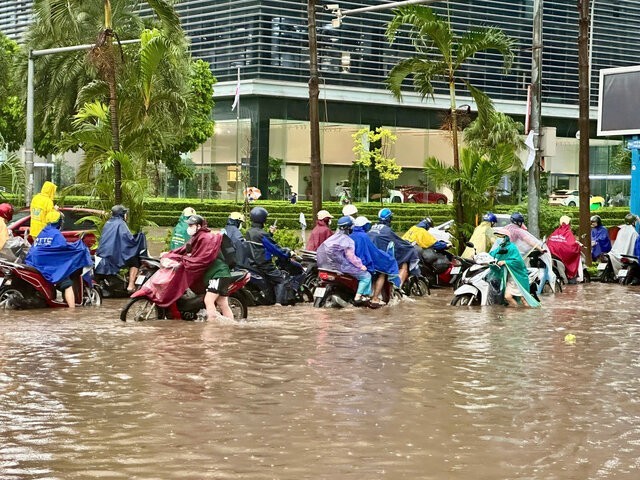 Đầu đường Dương Đình Nghệ ngập sâu, các phương tiện phải dắt bộ qua khu vực ngập. Ảnh: Tuấn Anh
