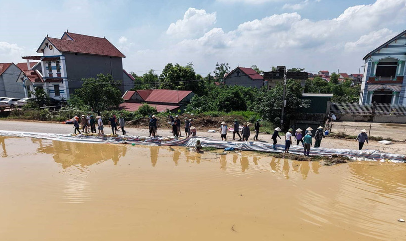 Người dân tập trung gia cố đê do nước sông Cầu dâng cao. 