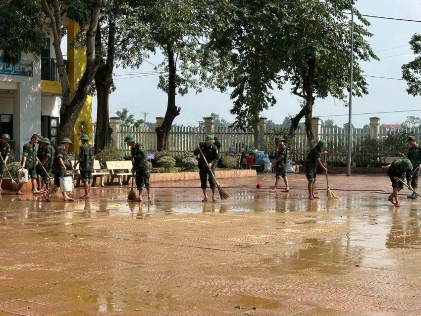 Các chiến sĩ cùng giáo viên các trường... phối hợp dọn bùn đất, thu gom rác thải.