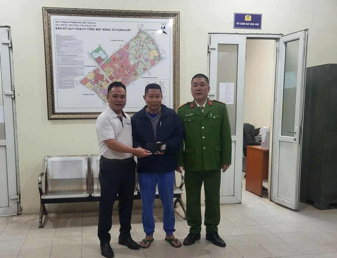 Đại diện Công an phường Thanh Xuân và anh Lã Thế Vinh (áo trắng) trao trả lại chiếc ví cho người bị mất.