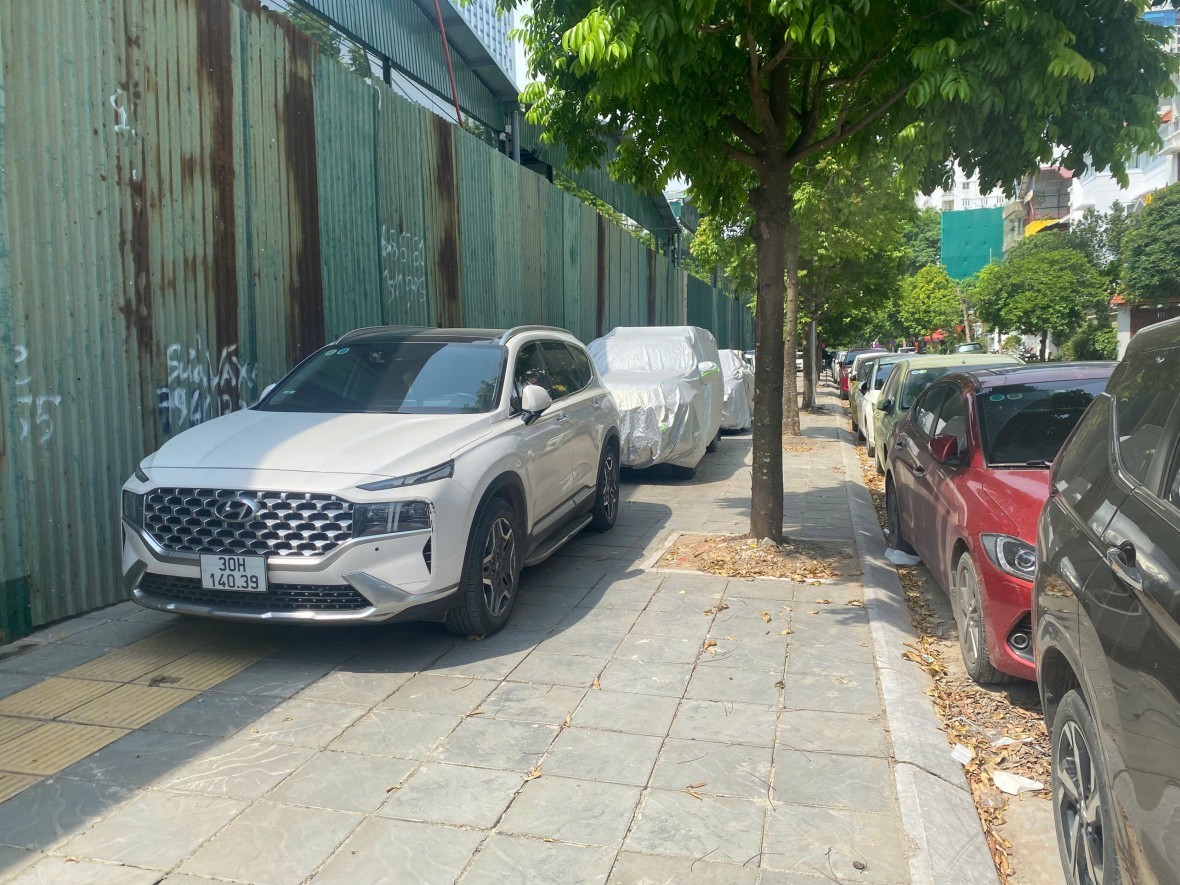 Xe ô tô đỗ hàng dài trên vỉa hè chỉ để lại một lối đi nhỏ cho người đi bộ trên đường Hoàng Quán Chi, phường Cầu Giấy.