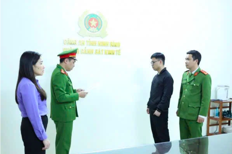 Cơ quan chức năng Ninh Bình công bố Quyết định khởi tố bị can đối với Nguyễn Đức Dương (áo đen). Ảnh: Công an Ninh Bình