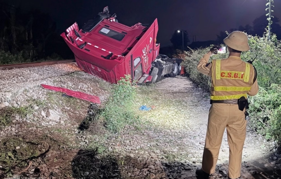 Đầu xe đầu kéo bị tông bay khỏi rơ moóc, nằm bên đường sắt. 