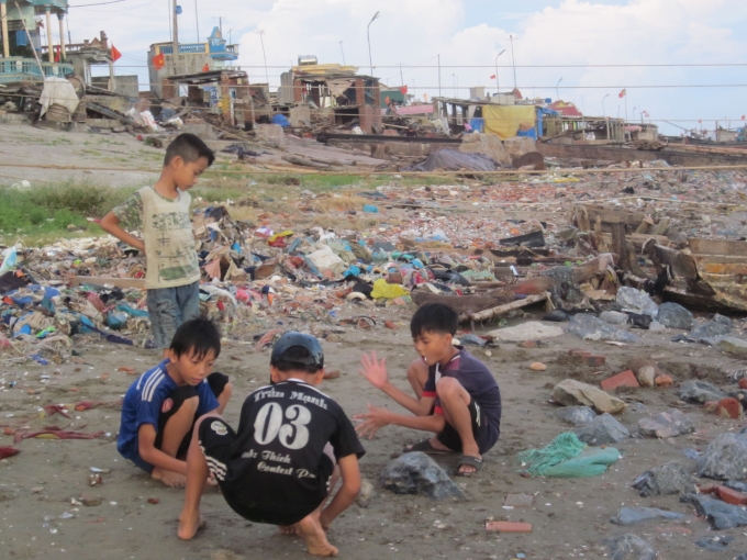 Trẻ em vui chơi b&ecirc;n những đống r&aacute;c ven biển.