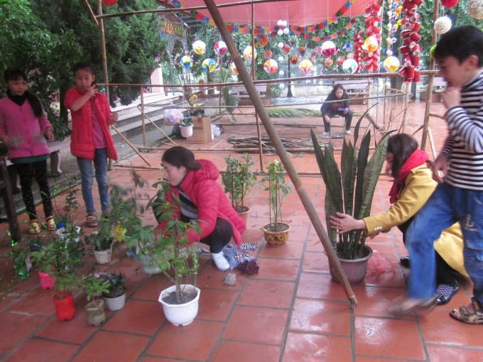 C&ocirc; tr&ograve; đang trồng c&acirc;y, chuẩn bị cho ng&agrave;y hội chợ.