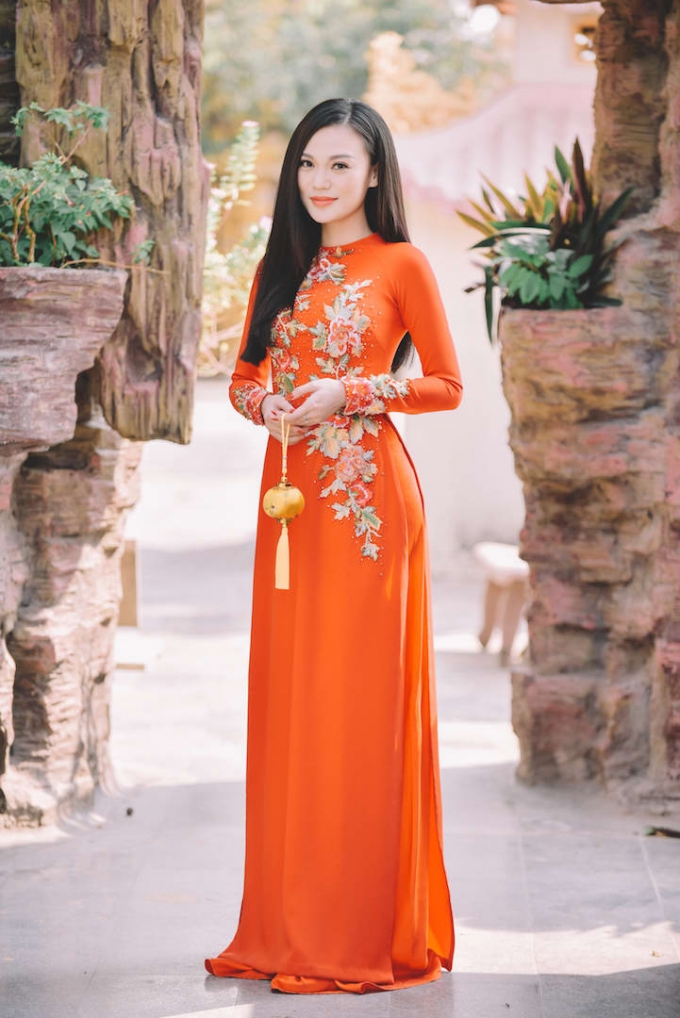 Cao Th&ugrave;y Linh ki&ecirc;u sa trong t&agrave; &aacute;o d&agrave;i m&agrave;u cam rực rỡ với nhiều họa tiết cầu kỳ ở phần ngực &aacute;o v&agrave; tay &aacute;o