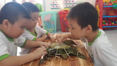 Học sinh một trường mầm non l&agrave;m quen với việc b&oacute;c b&aacute;nh chưng nh&acirc;n dịp Tết sắp đến Ảnh: BẢO L&Acirc;M