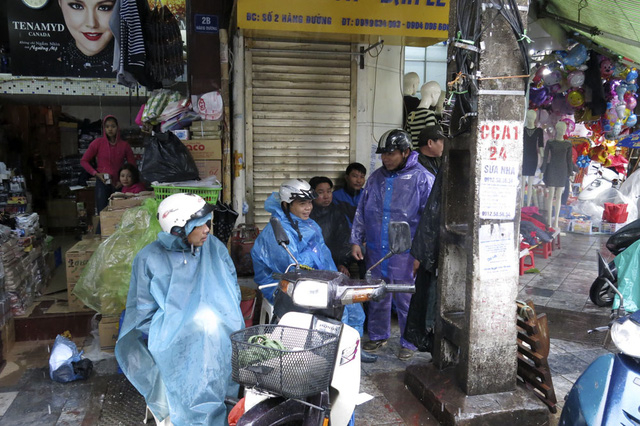 Mưa triền mi&ecirc;n n&ecirc;n rỗi việc, những người l&agrave;m nghề chở h&agrave;ng thu&ecirc; tr&ecirc;n phố H&agrave;ng Đường chỉ c&ograve;n biết ngồi t&aacute;n gẫu giết thời gian.