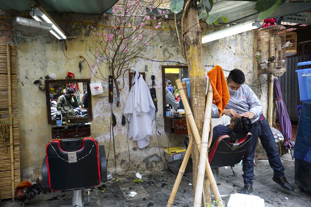 Hiệu cắt t&oacute;c vỉa h&egrave; phố H&agrave;ng Rươi với c&agrave;nh đ&agrave;o xu&acirc;n tr&ecirc;n tường.