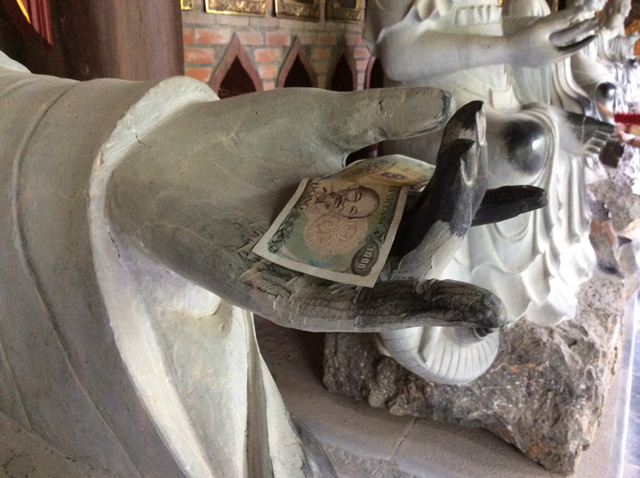 Người đi lễ ch&ugrave;a v&ocirc; tư đặt tiền l&ecirc;n tay phật ở ch&ugrave;a B&aacute;i Đ&iacute;nh.