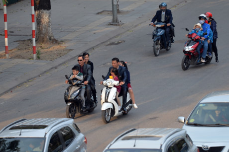 Hai gia đ&igrave;nh c&ugrave;ng kh&ocirc;ng đội mũ bảo hiểm vừa đi vừa n&oacute;i chuyện.