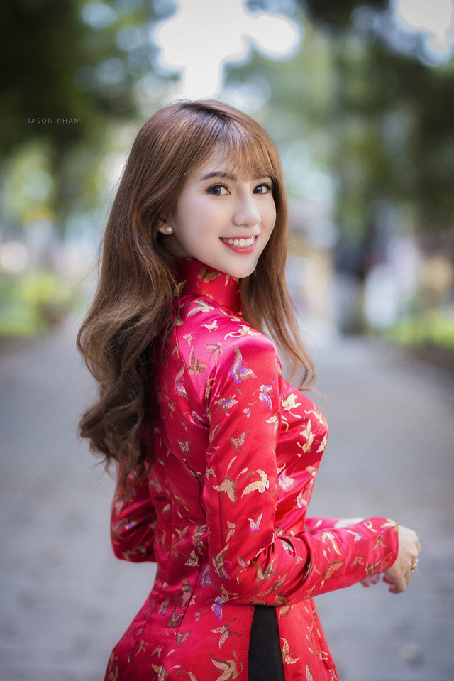 Trong bộ &aacute;o d&agrave;i đỏ, Hậu Giang dịu d&agrave;ng thả d&aacute;ng c&ugrave;ng nụ cười duy&ecirc;n, tr&ecirc;n tay l&agrave; phong bao l&igrave; x&igrave; v&agrave; hoa mai v&agrave;ng khoe sắc.