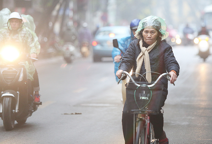 Một người phụ nữ đi xe đạp d&ugrave;ng t&uacute;i ni l&ocirc;ng đội l&ecirc;n đầu.