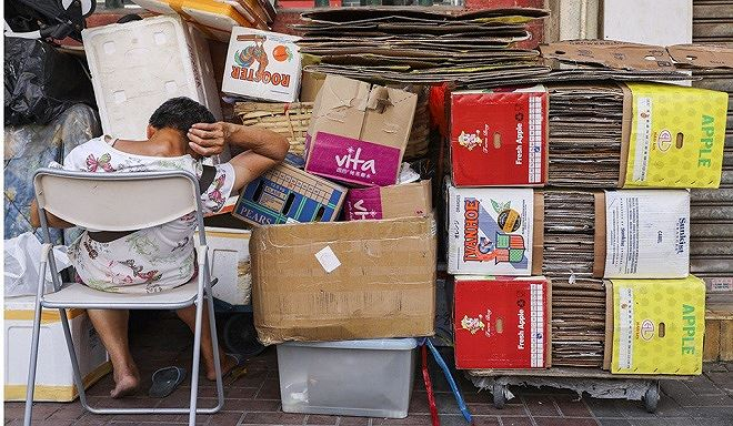 Một người cao tuổi ngủ gục b&ecirc;n c&aacute;c tấm b&igrave;a c&aacute;c t&ocirc;ng ở To Kwa Wan