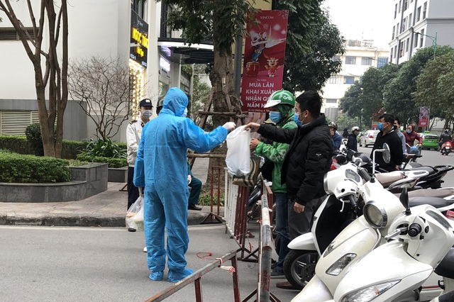 Người dân chỉ có thể nhận đồ đạc, thực phẩm gián tiếp qua nhân viên y tệ trực kiểm soát tại hàng rào phía ngoài. (Ảnh: Quốc Chính)