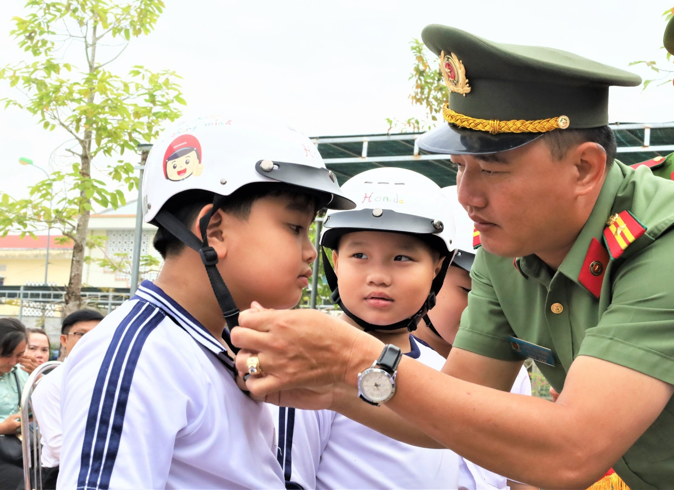 Thiếu tá Nguyễn Văn Phương, Trưởng Ban Thanh niên, Công an tỉnh Hậu Giang tặng mũ bảo hiểm cho các em học sinh tiểu học.