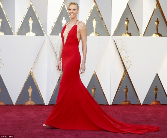 Charlize Theron hấp dẫn sải bước với chiếc đầm m&agrave;u đỏ cắt xẻ s&acirc;u ở ngực khoe hững hờ v&ograve;ng 1.
