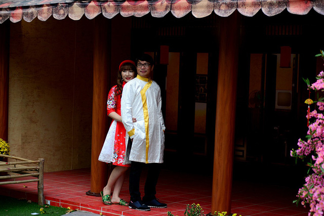 Hai bạn trẻ chụp h&igrave;nh dưới ng&ocirc;i nh&agrave; được thiết kế kiểu xưa.