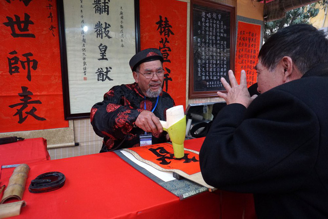 &Ocirc;ng đồ v&agrave; kh&aacute;ch c&ugrave;ng trao đổi trong khi viết chữ.