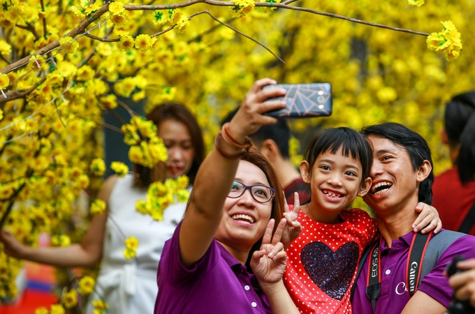 Gia đ&igrave;nh chị Hiếu (quận B&igrave;nh Thạnh) chụp h&igrave;nh lưu niệm tr&ecirc;n đường hoa mai Phạm Ngọc Thạch (quận 1).