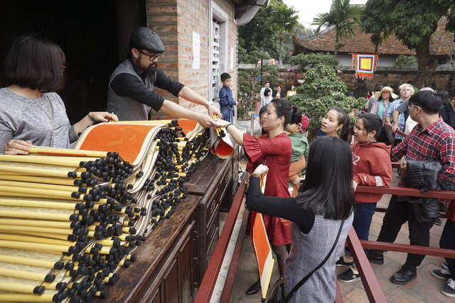 Người d&acirc;n đủ mọi lứa tuổi phải xếp h&agrave;ng mua giấy đỏ trước khi tới gặp c&aacute;c &ocirc;ng đồ