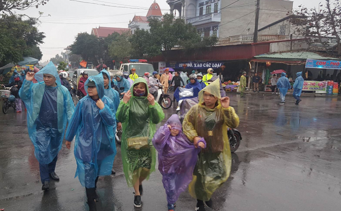 C&aacute;c du kh&aacute;ch đến với chợ Viềng phải mặc &aacute;o mưa chống lại cơn mưa nặng hạt chiều nay.