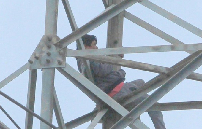 Người đ&agrave;n &ocirc;ng nghi ng&aacute;o đ&aacute; ngồi vắt vẻo tr&ecirc;n cột điện cao thế nhiều giờ đồng hồ.