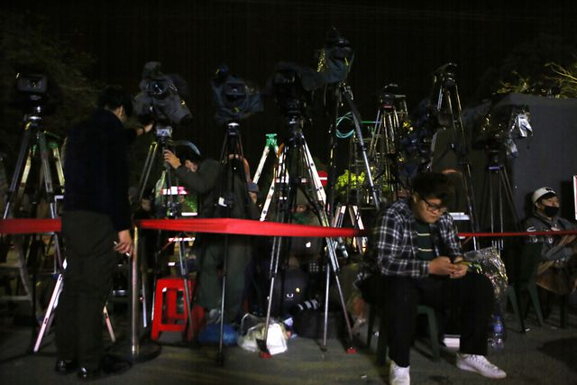 Ph&oacute;ng vi&ecirc;n nước ngo&agrave;i c&ugrave;ng thiết bị t&aacute;c nghiệp chờ đợi th&acirc;u đ&ecirc;m trước nh&agrave; ga.