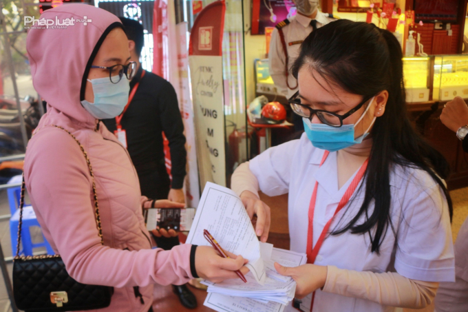 Một khách hàng nộp tờ khai y tế trước khi vào mua sản phẩm.