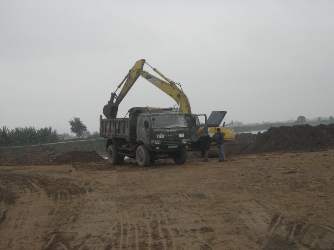 M&aacute;y x&uacute;c v&agrave; xe tải tiến h&agrave;nh việc san lấp.