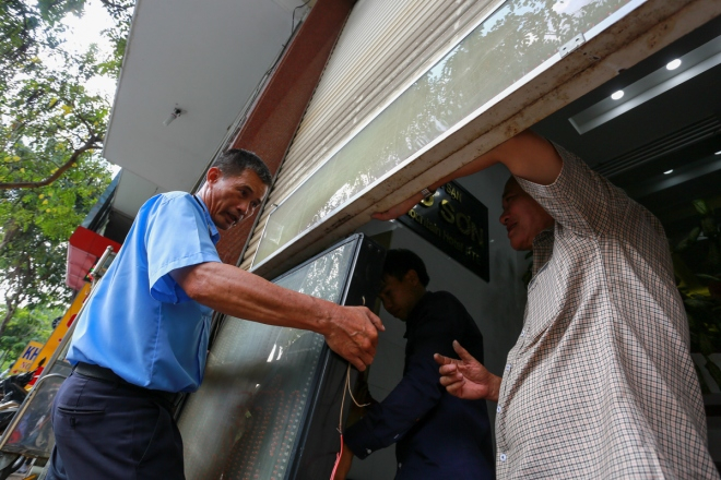 &Ocirc;ng T&agrave;i, chủ một kh&aacute;ch sạn c&ugrave;ng nh&acirc;n vi&ecirc;n tự th&aacute;o dỡ bảng hiệu quảng c&aacute;o để đặt v&agrave;o b&ecirc;n trong nh&agrave;.