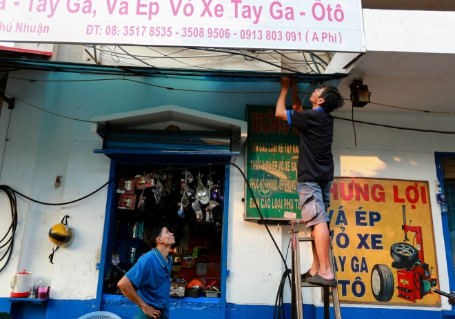 Anh Phi, chủ tiệm xe m&aacute;y, th&aacute;o dỡ tấm ph&ocirc;ng bạt lấn chiếm kh&ocirc;ng gian vỉa h&egrave;.&nbsp;Từ ng&agrave;y 25/2, trước những đợt kiểm tra, xử phạt thường xuy&ecirc;n nhằm