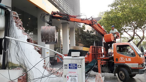 Lực lượng chức năng tháo dỡ bức tường cao 4 m trước C&ocirc;ng ty Hoa ti&ecirc;u hàng hải Khu vực 1 (đường Đinh Ti&ecirc;n Hoàng, phường B&ecirc;́n Nghé, qu&acirc;̣n 1, TP HCM) s&aacute;ng 6-3 Ảnh: SỸ Đ&Ocirc;NG