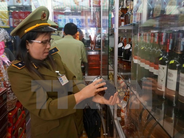 Lực lượng quản l&yacute; thị trường kiểm tra một cửa h&agrave;ng kinh doanh rượu. Ảnh: Phạm Cường/TTXVN