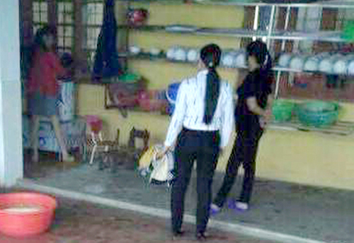 Hiệu trưởng Hằng (&aacute;o hồng) đang &ocirc;m rồi dốc đầu ch&aacute;u b&eacute; v&agrave;o m&aacute;y vặt l&ocirc;ng g&agrave; v&agrave; h&ocirc; cắm điện để &ldquo;ch&aacute;u kh&ocirc;ng kh&oacute;c nữa&rdquo;. Ảnh cắt từ clip do gia đ&igrave;nh cung cấp.