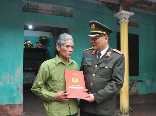 Thiếu tướng T&ocirc; &Acirc;n X&ocirc; - Gi&aacute;m đốc C&ocirc;ng an tỉnh Bắc Giang trao quyết định thăng cấp bậc h&agrave;m l&ecirc;n Trung t&aacute; cho gia đ&igrave;nh anh Nguyễn Quang Luận