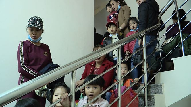Trẻ ngồi cả tr&ecirc;n cầu thang chờ đến lượt v&agrave;o kh&aacute;m.