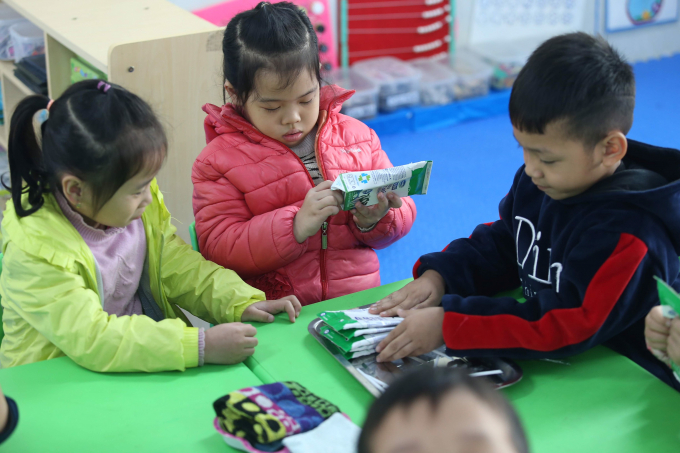 C&aacute;c học sinh c&ugrave;ng gấp vỏ hộp sữa gọn g&agrave;ng sau khi uống sữa học đường.