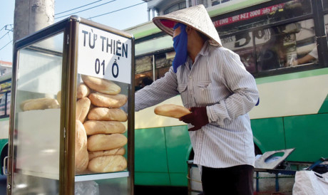 Một người mua ve chai đang lấy b&aacute;nh m&igrave; từ thiện.